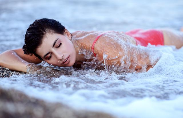 woman laying in the ocean with bikini